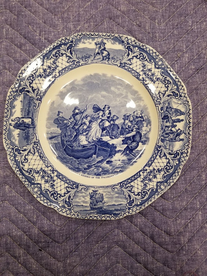Crown Ducal (after Joseph Andrews, after Peter Frederick Rothermel), Dinner Plate: Landing of the Pilgrims, from the series Colonial Times, 1930-1940, ca.
glazed earthenware, 10 3/8 x 10 3/8 x 3/4 in.
Ceramic transferware dinner plate; ivory with blue color printed pattern, circular, scalloped rim with circular well; rim with diamond and foliate printed pattern and vignettes, each depicting native american and pilgrim imagery: Pocahontas Saving Life of John Smith; American Indian; Mayflower in Plymouth Harbor; Return of the Mayflower.  Central image depicts Landing of the Pilgrims.  Reverse image depicts Pilgrim Exiles.
2019.19.04
ADDITIONAL INFORMATION: Acquired for exhibition: A Band of Exiles on the Wild New England Shore; The Place of Peter Frederick Rothermel's The Landing of the Pilgrims in America's National Memory
March-May 2014
Additional documented makers: Gordon Pottery Works, Tunstall, Stoke-on-Trent